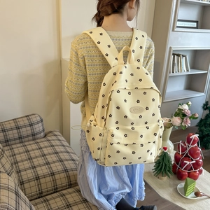 Detail of a beige floral canvas backpack with black flower patterns for students