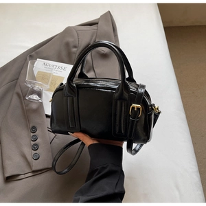 Détail du sac Boston noir brillant avec boucles dorées et bandoulière en cuir ajustable