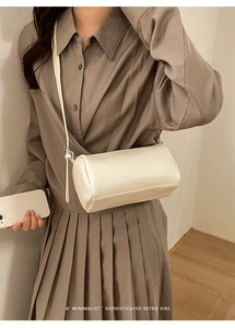 Detailed view of cream-colored cross-body cylindrical bag with lychee pattern leather