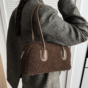 Detail of plush brown underarm bag with leather strap on a grey wool coat