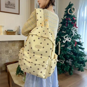 Detail of cream floral backpack featuring black flower prints and drawstring side pockets