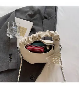 Détail du sac à main plissé crème avec chaîne argentée et pendentif en perles