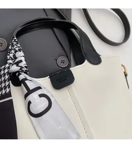 Detailed view of white bucket bag with black leather straps and houndstooth scarf