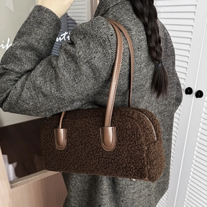 Shoulder view of dark brown faux shearling hobo bag with leather straps on a wool coat
