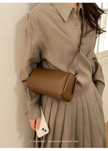 Detailed shot of dark brown lychee leather texture on a cylindrical crossbody bag