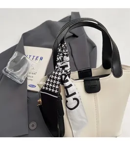 Detail of cream bucket bag with houndstooth silk scarf handle and leather logo flap