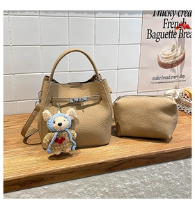 Detail view of beige lychee texture bucket bag and matching pouch on a wooden surface