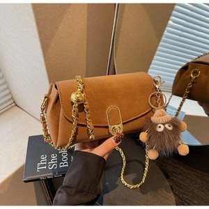 Détail du sac bandoulière marron caramel avec chaîne dorée et breloque monstre en peluche