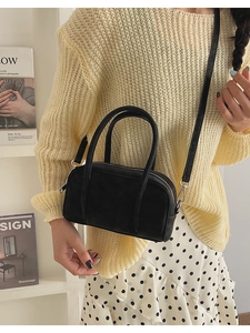 Detail of a black matte mini crossbody bag with silver hardware on a model's arm