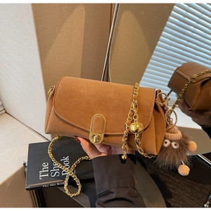 Détail du sac bandoulière en daim marron avec fermoir doré et pendentif monstre