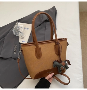 Detalle de bolso cubo de lona con adornos de cuero y colgante de caballo en tela
