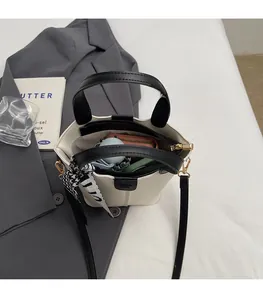 Spacious interior of a stylish off-white bucket bag holding a wallet and umbrella