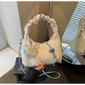 Détail du sac hobo plissé blanc avec breloque cœur perle et lanière en dentelle