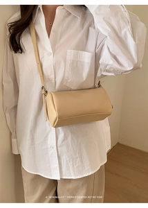 Model view of beige cylinder crossbody bag with pebble leather texture and retro vibe