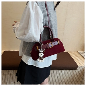 Detail of burgundy suede Boston bag with gold buckle and schnauzer plush pendant charm