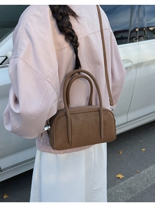 Detailed view of a brown leather bowling bag with twin handles and adjustable shoulder strap
