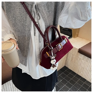 Detail view of burgundy faux suede shell bag featuring gold hardware and a cute dog charm