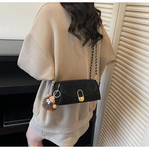 Détail du sac bandoulière en cuir noir avec fermoir doré et breloque hérisson en peluche