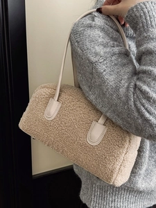 Beige shearling shoulder bag with leather handles shown on a model in grey knitwear