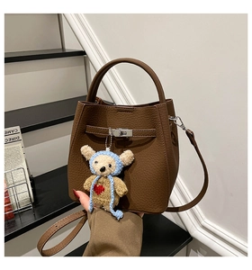Detailed view of dark brown litchi grain leather bucket bag with cute bear charm