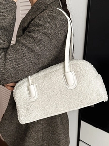 Minimalist white faux fur shoulder bag with leather handles shown in interior setting
