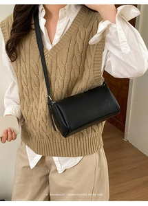 Detail of lychee pattern leather and silver hardware on a black cylindrical crossbody bag