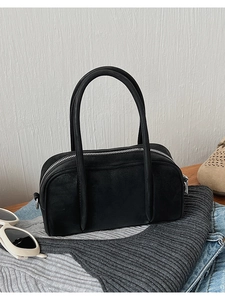 Close-up of minimalist black matte bowling bag with slim handles on wooden surface