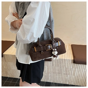 Detail of dark brown suede shell bag with gold buckle and cute dog charm on side
