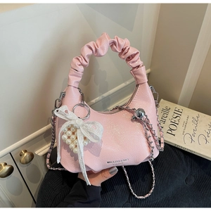 Détail du sac croissant rose avec anse froncée, nœud en dentelle et breloque perle