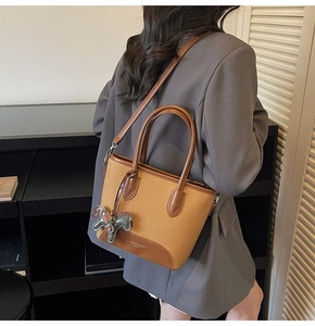 Detalle del bolso de cubo bicolor con colgante de caballo en modelo con blazer gris