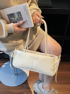 Chic beige baguette shoulder bag with side bow detail and stylish brand emblem