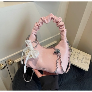 Détail d'un sac selle rose avec poignée plissée, nœud en dentelle et chaîne argentée