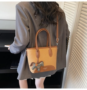 Detalle del bolso tote de lona con ribetes de cuero y colgante de caballo en modelo