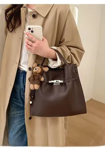 Detail of dark brown lychee leather handbag with silver lock and bear charm