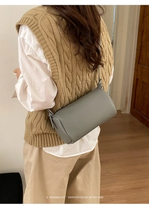 Detailed view of gray cylinder crossbody bag with lychee pattern and thin leather strap