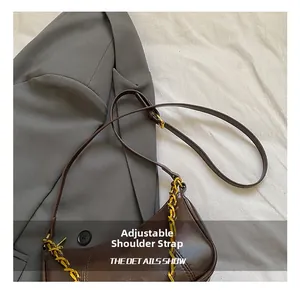 Detail showing the adjustable leather shoulder strap and gold-tone chain on the brown bag