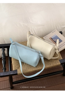 Detail shot of light blue and beige cylinder bags with lychee grain leather texture
