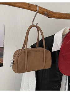 Detail of vintage brown leather handbag featuring a smooth zipper and long shoulder straps