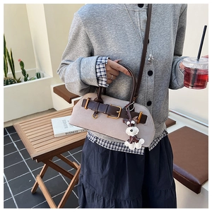 Boston style bag with schnauzer charm and shoulder strap shown in an outdoor setting