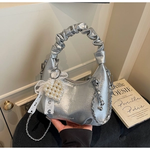 Détail du sac à main plissé argenté avec pendentif cœur en perles et chaîne métallique