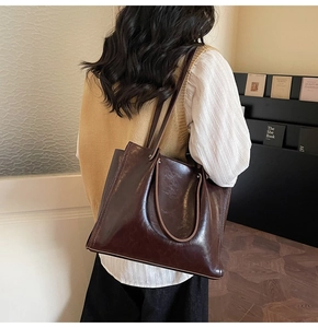 Detail of glossy dark brown tote bag showing smooth faux leather texture and craftsmanship