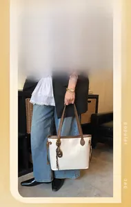 Detail shot of white tote bag with brown straps showing large capacity and commuter style