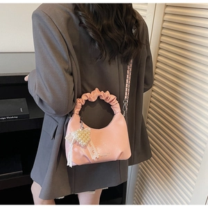 Vue détaillée du sac hobo rose avec poignée à froufrous, breloque coeur et nœud dentelle