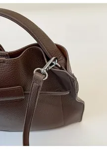 Detail of a dark brown pebble leather handbag with silver metal twist lock and strap