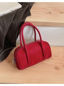 Macro detail of red matte leather bowling bag with silver zipper on wooden steps