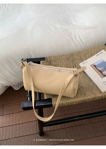 Detail of minimalist lychee pattern cylinder bag in beige on a textured bench