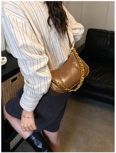 Brown vintage baguette bag with chunky gold chain detail shown on shoulder