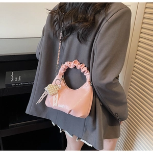 Détail du sac à main rose avec poignée plissée, nœud en perles et chaîne argentée