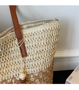 Close-up of woven straw tote bag with leather strap, zipper closure and wooden beads