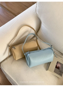 Detail of minimalist cylinder bags in yellow and blue leather on a white sofa